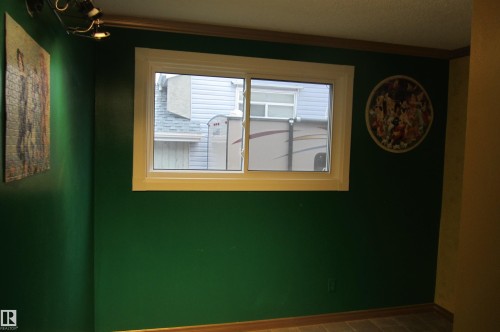 White-trimmed window providing natural light, set within a vibrant green wall with wood trim - 3814 37 Avenue, Leduc, AB - Indoor Photo Showing Other Room