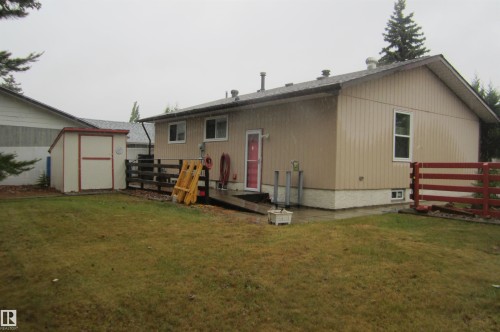 Rear exterior featuring tan siding and a red entry door - 3814 37 Avenue, Leduc, AB - Outdoor With Exterior