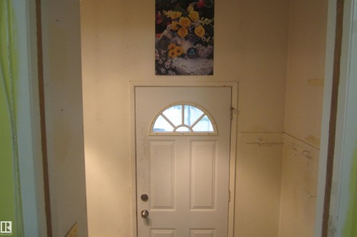 Entryway featuring a white door with an arched window and decorative grilles - 3814 37 Avenue, Leduc, AB - Indoor Photo Showing Other Room