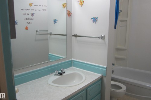 Bathroom featuring a single vanity with a laminate countertop, integrated sink, and dual-handle faucet - 3814 37 Avenue, Leduc, AB - Indoor Photo Showing Bathroom