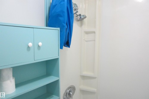White shower stall featuring an integrated shelving system and a chrome showerhead - 3814 37 Avenue, Leduc, AB - Indoor