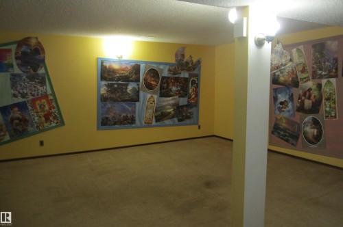 Carpeted room featuring light yellow walls and a structural support column with wall-mounted lighting fixtures - 3814 37 Avenue, Leduc, AB - Indoor Photo Showing Other Room