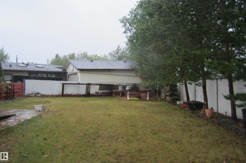 Expansive backyard featuring a lush lawn, mature trees, and privacy fencing - 3814 37 Avenue, Leduc, AB - Outdoor
