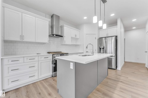 Modern kitchen featuring white shaker cabinetry, stainless steel appliances, a white subway tile backsplash, and a central island with an integrated sink and pendant lighting - 1972 210 Street, Edmonton, AB - Indoor Photo Showing Kitchen With Upgraded Kitchen