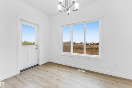 Room featuring wood-finish flooring, a contemporary chandelier, a multi-pane window, a paneled door with glass insert, and white baseboards - 1972 210 Street, Edmonton, AB - Indoor Photo Showing Other Room