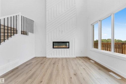 Bright interior featuring high ceilings, wood-finish flooring, and a contemporary electric fireplace with a decorative shiplap surround - 1972 210 Street, Edmonton, AB - Indoor Photo Showing Living Room With Fireplace