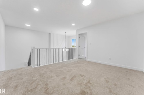 Carpeted upper-level landing featuring a white painted railing with black balusters, recessed lighting, and a white interior door - 1972 210 Street, Edmonton, AB - Indoor Photo Showing Other Room