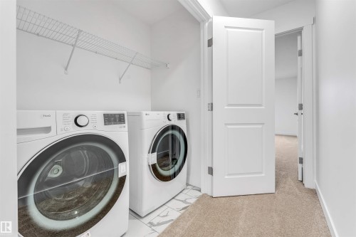 Dedicated laundry closet featuring a wire storage shelf, white wall paint, and tile flooring - 1972 210 Street, Edmonton, AB - Indoor Photo Showing Laundry Room