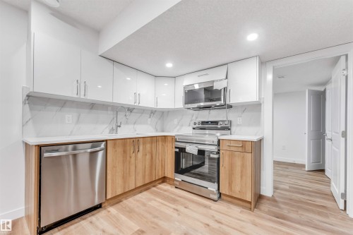 Contemporary kitchen with two-tone cabinetry, stainless steel appliances, white quartz countertops, and a full-height marble-look backsplash - 1972 210 Street, Edmonton, AB - Indoor Photo Showing Kitchen