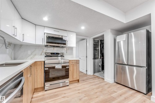 Kitchen featuring white upper cabinetry, wood-finish lower cabinetry, a stainless steel electric range, an over-the-range microwave, and a stainless steel French door refrigerator - 1972 210 Street, Edmonton, AB - Indoor Photo Showing Kitchen