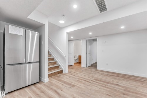 Open-concept space featuring light wood-finish flooring, recessed lighting, and a modern stainless steel refrigerator - 1972 210 Street, Edmonton, AB - Indoor Photo Showing Other Room