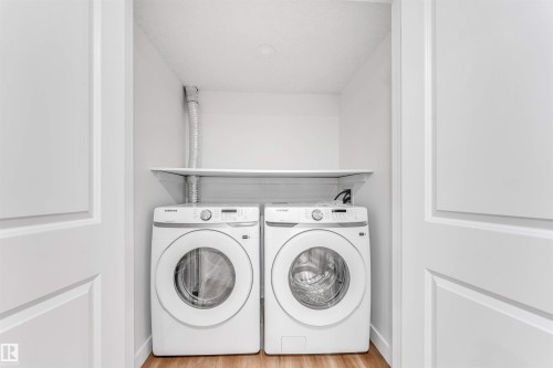 Dedicated laundry closet featuring a built-in shelf and wood-finish flooring - 1972 210 Street, Edmonton, AB - Indoor Photo Showing Laundry Room