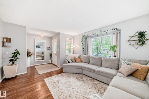 Light-filled living area featuring wood-finish flooring, a large picture window, and a white ceiling - 17233 88 Street, Edmonton, AB - Indoor Photo Showing Living Room