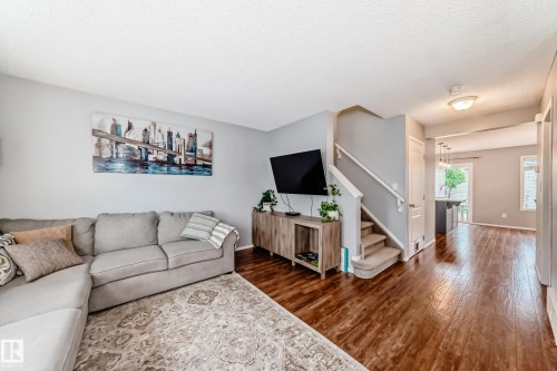 Spacious living area featuring wood-finish flooring, light gray wall paint, and a built-in staircase with carpeted treads - 17233 88 Street, Edmonton, AB - Indoor Photo Showing Living Room