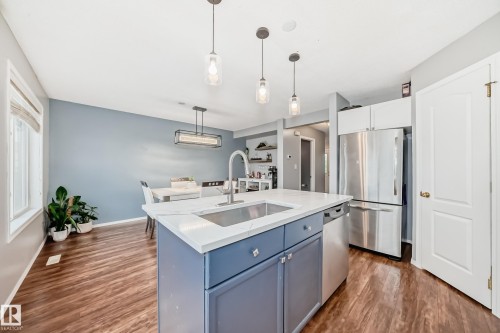 Kitchen featuring a central island with a built-in stainless steel sink, a quartz countertop, and blue cabinetry - 17233 88 Street, Edmonton, AB - Indoor Photo Showing Kitchen With Upgraded Kitchen