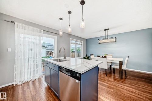 Kitchen island featuring a white countertop, undermount stainless steel sink, and integrated dishwasher - 17233 88 Street, Edmonton, AB - Indoor Photo Showing Kitchen