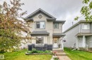 Two-story residence featuring light-colored siding, a stone facade accent, and dark shingle roofing - 17233 88 Street, Edmonton, AB  - Outdoor With Facade 