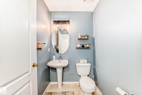 Powder room with pedestal sink, oval mirror, and wall-mounted light fixture - 17233 88 Street, Edmonton, AB - Indoor Photo Showing Bathroom