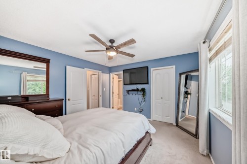 Carpeted bedroom featuring a ceiling fan with integrated lighting, a window with blinds and drapes, and white bi-fold closet doors - 17233 88 Street, Edmonton, AB - Indoor Photo Showing Bedroom