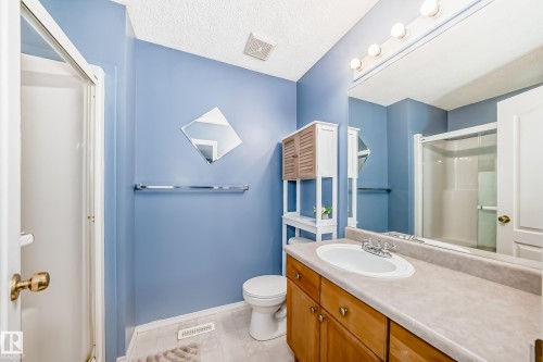 Bathroom featuring a single vanity with wood-finish cabinetry, a large mirror, and a shower enclosure - 17233 88 Street, Edmonton, AB - Indoor Photo Showing Bathroom