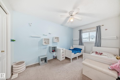 Light blue-painted room featuring a window with a white frame, a ceiling fan, and light-toned carpet flooring - 17233 88 Street, Edmonton, AB - Indoor Photo Showing Bedroom