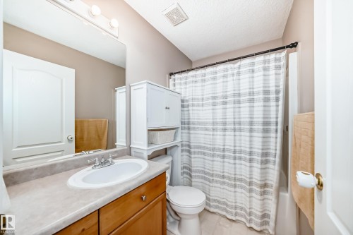 Bathroom featuring a vanity with a white oval sink, wood-finish cabinetry, a large wall mirror, and an overhead lighting fixture - 17233 88 Street, Edmonton, AB - Indoor Photo Showing Bathroom