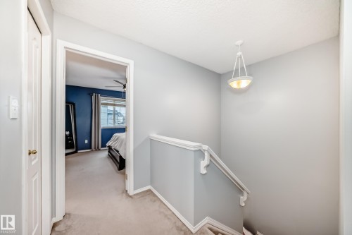 Carpeted hallway featuring a white spindle railing and a contemporary pendant light fixture - 17233 88 Street, Edmonton, AB - Indoor Photo Showing Other Room