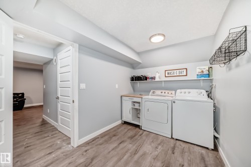 Laundry area featuring wood-finish flooring, light gray walls, and white baseboards - 17233 88 Street, Edmonton, AB - Indoor Photo Showing Laundry Room