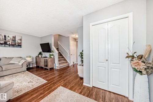 Main living area featuring rich wood-finish flooring, light gray wall tones, and a white bi-fold closet door - 17233 88 Street, Edmonton, AB - Indoor Photo Showing Living Room