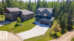Contemporary two-story residence featuring dark blue vertical siding, a stone accent facade, and a dark asphalt shingle roof - 