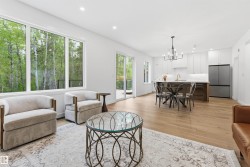 Open-concept living area with wood-finish flooring, recessed lighting, and large windows - 