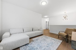 Bright interior space featuring wood-finish flooring, white walls, and contemporary lighting fixtures - 
