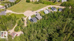 Cul-de-sac property surrounded by mature trees, featuring a paved road, and expansive green spaces - 