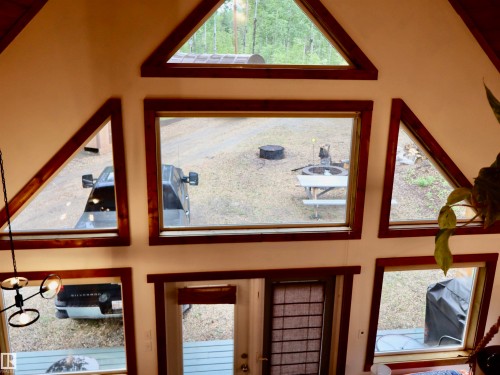 Vaulted ceiling with multiple windows featuring wood trim, geometric window shapes, and a multi-light chandelier - #20 59316 Rr 54, Rural Barrhead County, AB 