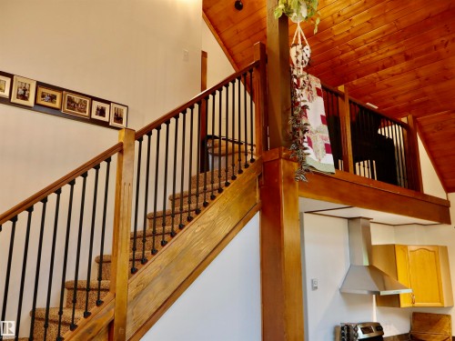 Wood-finish staircase featuring black metal spindles and a carpeted tread - #20 59316 Rr 54, Rural Barrhead County, AB 