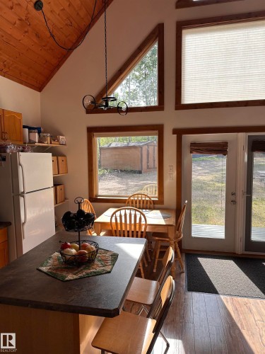 Vaulted wood-paneled ceiling with exposed beams, wood-finish flooring, and a kitchen island featuring a dark countertop - #20 59316 Rr 54, Rural Barrhead County, AB 