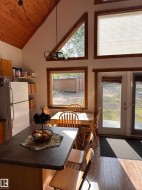 Vaulted wood-paneled ceiling with exposed beams, wood-finish flooring, and a kitchen island featuring a dark countertop - 