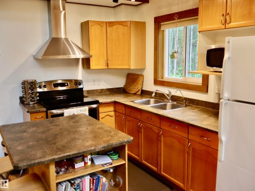 Kitchen featuring wood cabinetry, a double basin stainless steel sink, a stainless steel range with overhead hood vent, and stone-look countertops - #20 59316 Rr 54, Rural Barrhead County, AB 