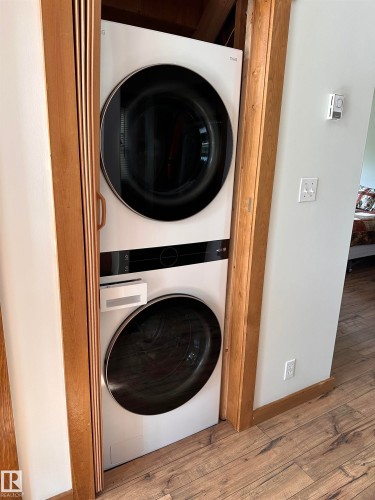 Stackable white washer and dryer unit within a dedicated wood-trimmed alcove - #20 59316 Rr 54, Rural Barrhead County, AB 