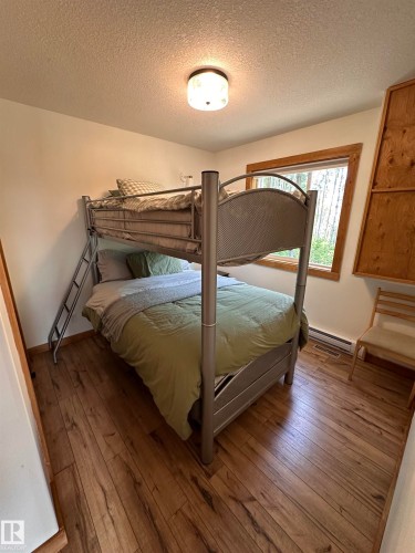 Bedroom featuring wood-finish flooring, a window with wood trim, and built-in wood shelving - #20 59316 Rr 54, Rural Barrhead County, AB 