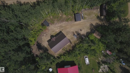 Aerial view of a property featuring a brown-roofed structure, surrounded by mature trees - #20 59316 Rr 54, Rural Barrhead County, AB 