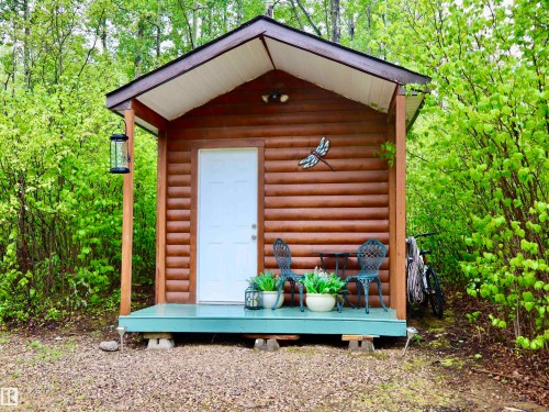 Log cabin exterior featuring horizontal log siding and a pitched roof - #20 59316 Rr 54, Rural Barrhead County, AB 