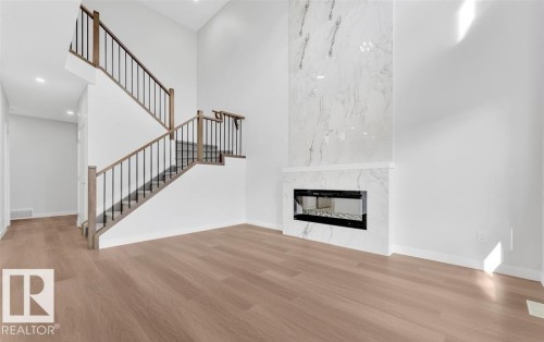 Two-story entry featuring wood-finish flooring and a contemporary staircase with dark metal balusters - 3025 39 Avenue, Beaumont, AB - Indoor Photo Showing Living Room With Fireplace