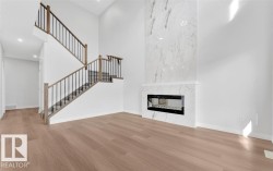 Two-story entry featuring wood-finish flooring and a contemporary staircase with dark metal balusters - 
