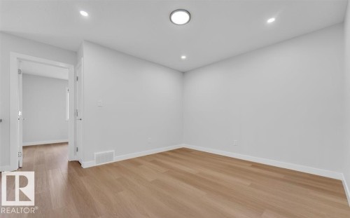 Neutral-toned walls complementing wood-finish flooring - 3025 39 Avenue, Beaumont, AB - Indoor Photo Showing Other Room