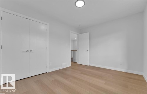 Neutral-toned room featuring light wood-finish flooring, white walls, and a ceiling-mounted light fixture - 3025 39 Avenue, Beaumont, AB - Indoor Photo Showing Other Room