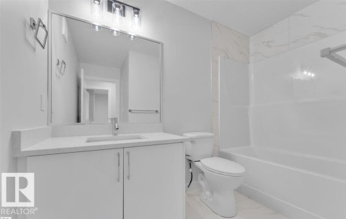 Bathroom featuring a white vanity with a light-toned countertop, an undermount sink, and a rectangular mirror - 3025 39 Avenue, Beaumont, AB - Indoor Photo Showing Bathroom