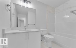 Bathroom featuring a white vanity with a light-toned countertop, an undermount sink, and a rectangular mirror - 