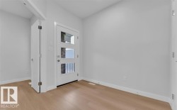 Entryway featuring a white door with three frosted glass panels, light wood-finish flooring, and white baseboards - 