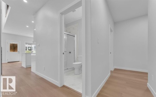 Contemporary interior hallway with wood-finish flooring, recessed lighting, white walls, and a full bathroom featuring a glass-enclosed shower with tiled walls - 3025 39 Avenue, Beaumont, AB - Indoor Photo Showing Other Room